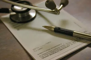 Prescription pad, pen and stethoscope on a desk