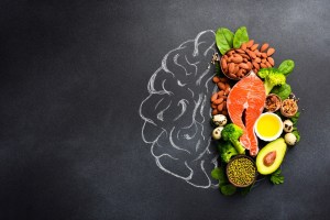 A picture of the brain drawn in chalk with various food products: fish, meat, nuts, vegetables and greens. Healthy food.