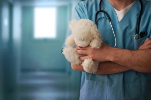 Male nurse holding a white teddy bear