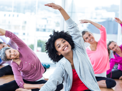 A diverse group of women participating in a group exercise or fitness class, likely focused on stretching or yoga.