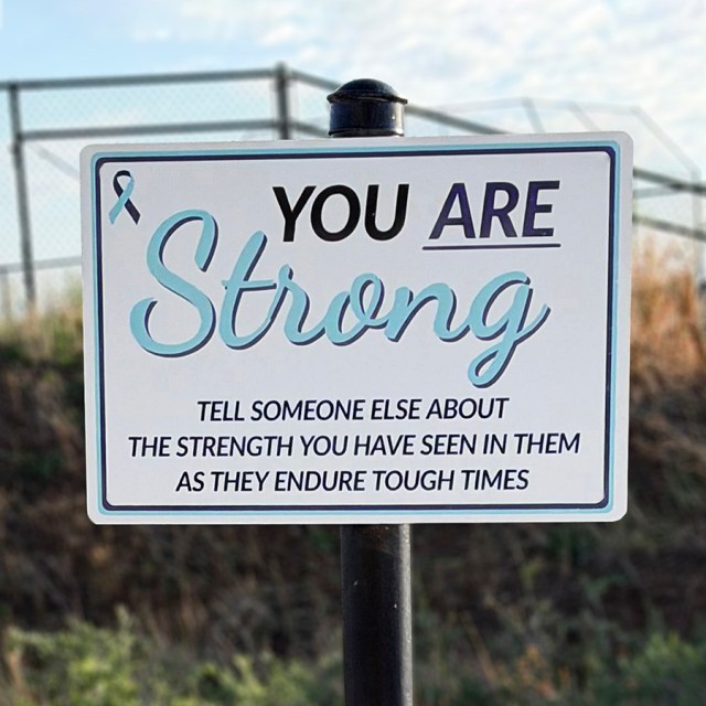 A trail sign that says, "You are strong. Tell someone else about strength you have seen in them as they endure tough times"