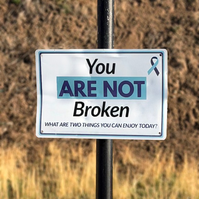 A trail sign that says, "You are not broken. What are two things you can enjoy today?"